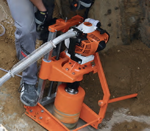 Bohren 90&deg; am verlegten Rohr. Das Kernbohrger&auml;t wird mit dem Rohrfu&szlig; zwischen Betonrohr und Grabenwand geklemmt. Zus&auml;tzliche Sicherung mit Erdn&auml;geln.